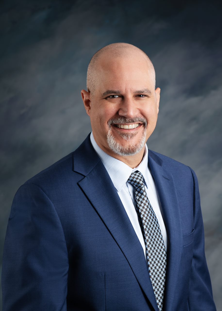 Dean of the school of public health smiling with a blue backround