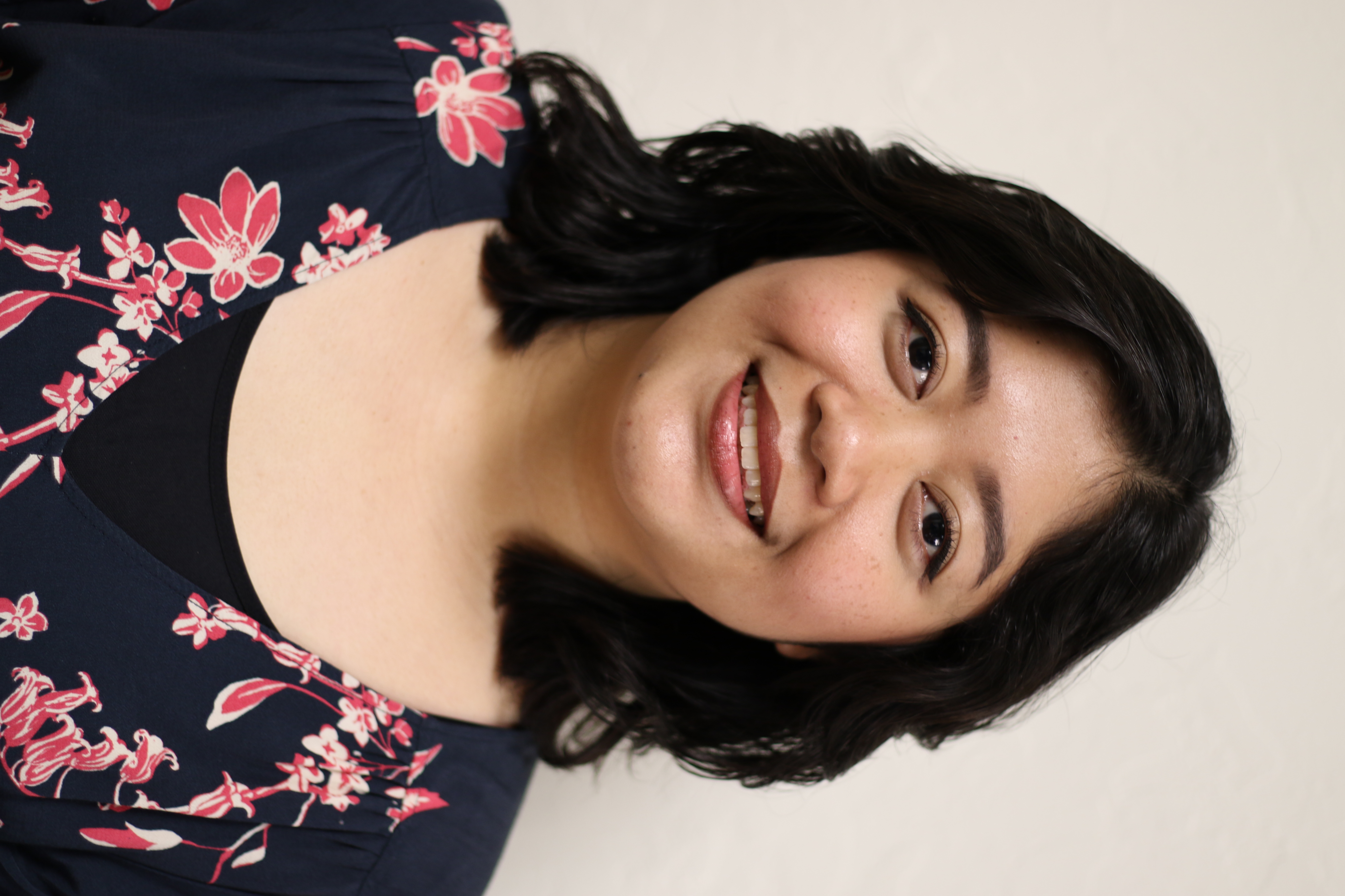 Princess smiling with a white background. wearing a black and purple shirt