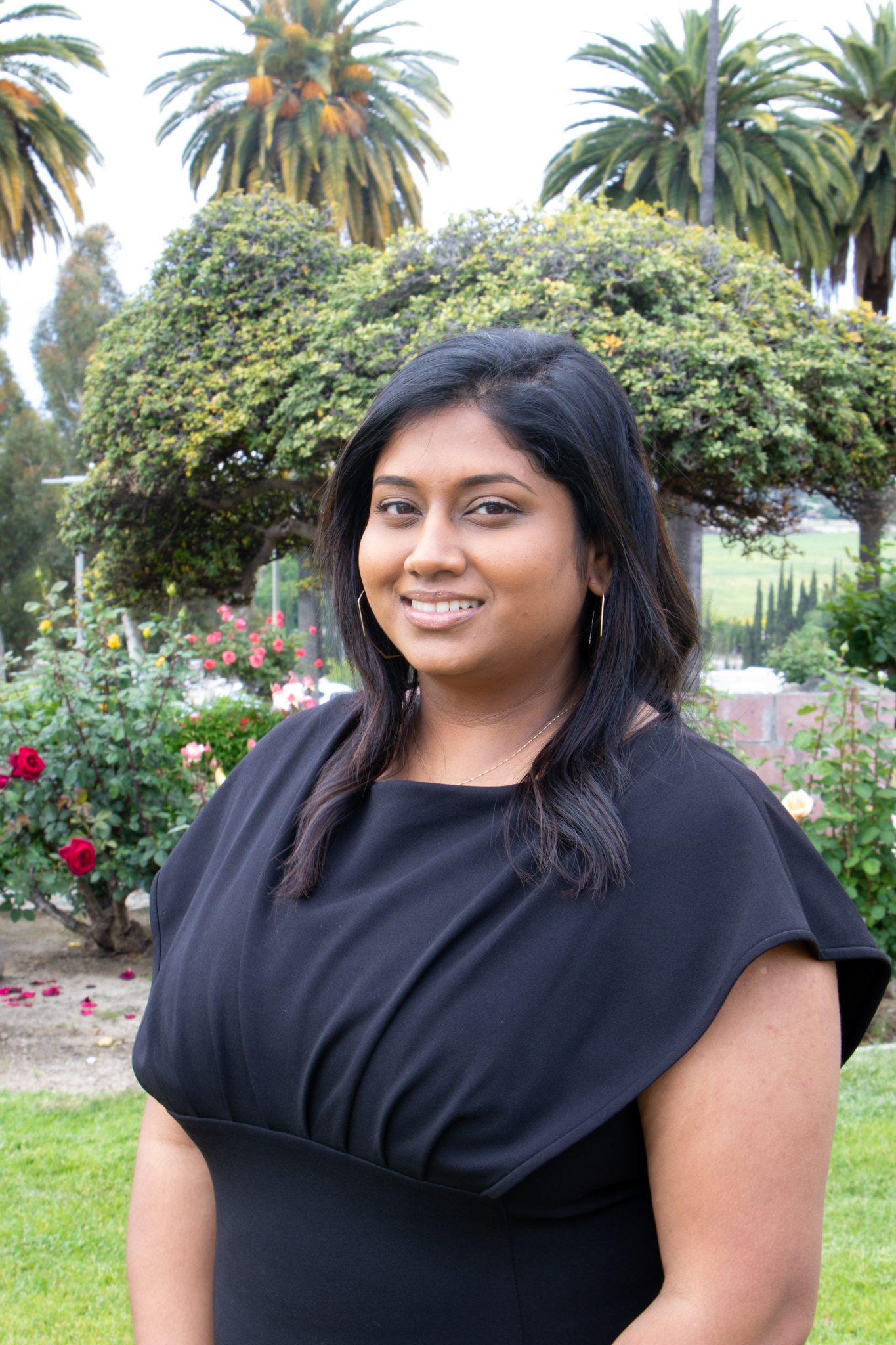 Nishita smiling in front of trees with a black shirt