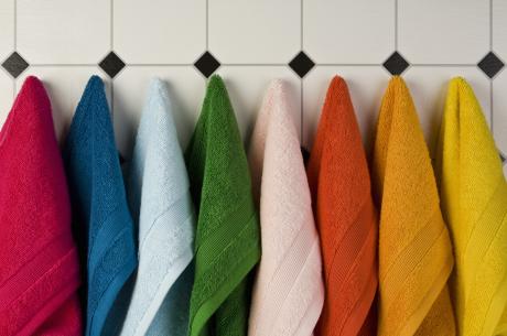 Multi colored towels hanging in a row on the wall 