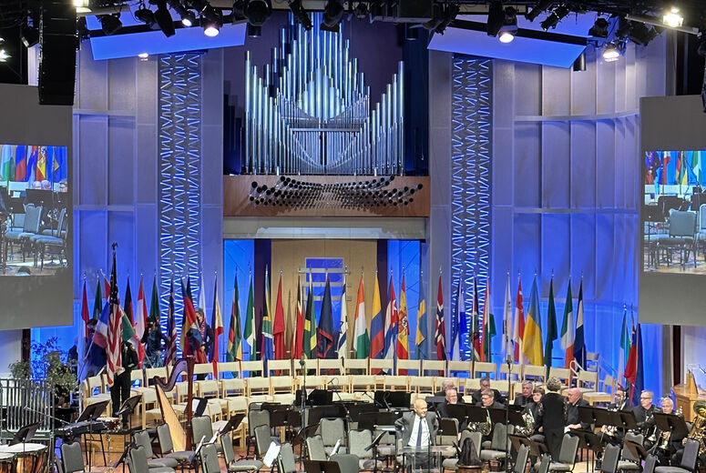 Flags on a stage with people sitting and watching