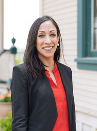 Woman in a black suite wearing a red shirt