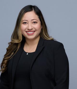 flor smiling with black shirt and blazer in front of gray background