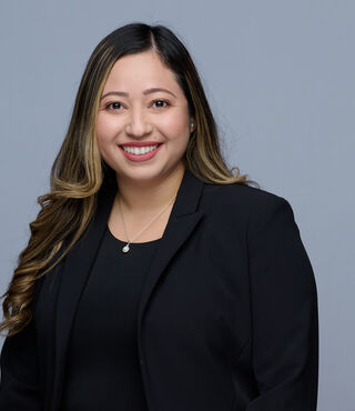 flor smiling with black shirt and blazer in front of gray background