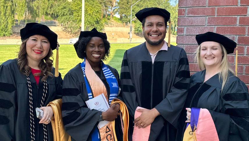graduates in black regalia smiling